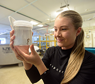 a girl inspects a seahorse in a jar